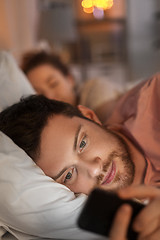 Image showing man using smartphone while girlfriend is sleeping