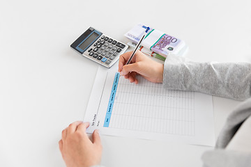 Image showing hands with tax form, calculator and money on table