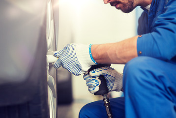 Image showing mechanic with screwdriver changing car tire