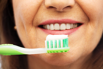 Image showing senior woman with toothbrush brushing her teeth