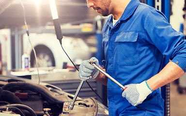 Image showing mechanic man with wrench repairing car at workshop