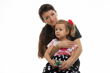 Image showing Four-year-old daughter sits on mother\'s lap, white background