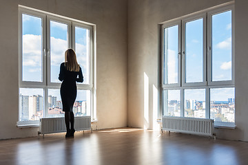 Image showing A girl looks into large stained glass windows in an empty apartment