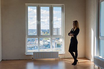 Image showing Slender girl stands at a large stained glass window in an empty room