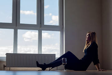 Image showing Sad girl with sitting on the floor of an empty room with a glass of wine