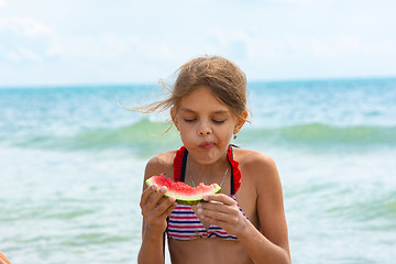 Image showing A girl eats a watermelon on the beach