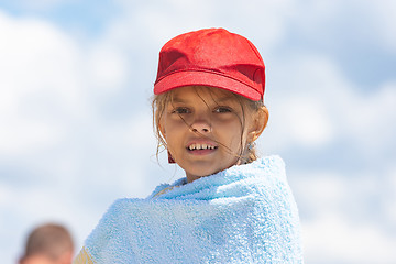 Image showing Portrait of a girl in a red cap wrapped in a towel against the sky