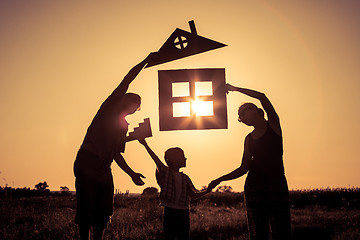 Image showing Happy family standing on the field at the sunset time. They buil