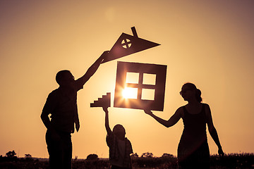 Image showing Happy family standing on the field at the sunset time. They buil