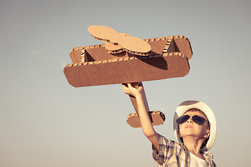 Image showing Little boy playing with cardboard toy airplane in the park at th