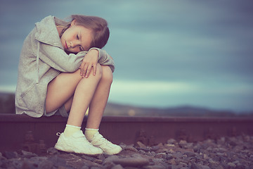 Image showing Portrait of young sad girl sitting outdoors  on the railway