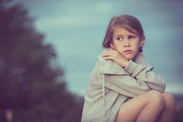 Image showing Portrait of young sad girl sitting outdoors  on the railway