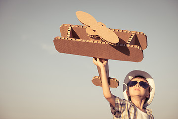 Image showing Little boy playing with cardboard toy airplane in the park at th