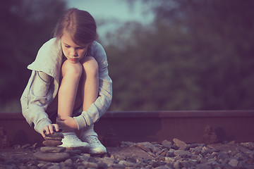 Image showing Portrait of young sad girl sitting outdoors  on the railway