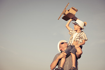 Image showing Father and son playing with cardboard toy airplane in the park a