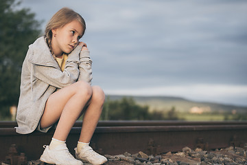 Image showing Portrait of young sad girl sitting outdoors  on the railway