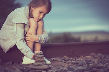 Image showing Portrait of young sad girl sitting outdoors  on the railway