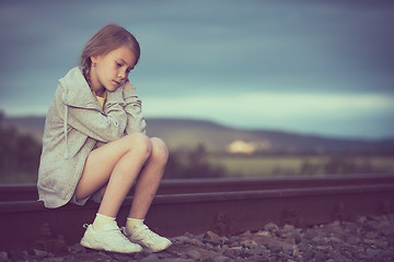 Image showing Portrait of young sad girl sitting outdoors  on the railway