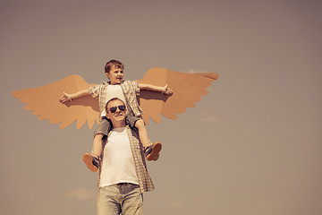Image showing Father and son playing with cardboard toy wings