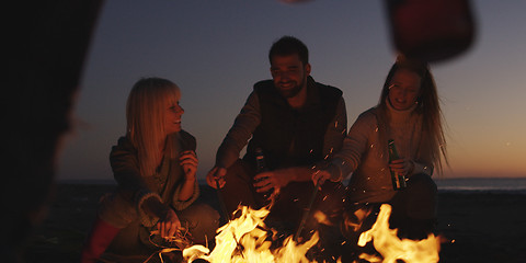 Image showing Young Friends Making A Toast With Beer Around Campfire at beach
