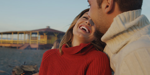 Image showing Loving Young Couple Sitting On The Beach beside Campfire drinkin