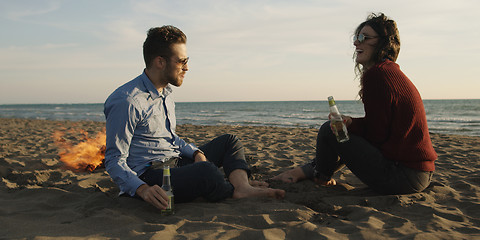 Image showing Loving Young Couple Sitting On The Beach beside Campfire drinkin