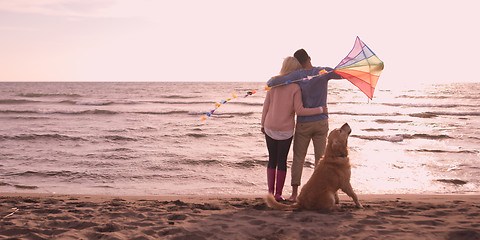 Image showing couple with dog having fun on beach on autmun day