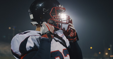 Image showing American Football Player Putting On Helmet on large stadium with