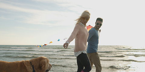 Image showing couple with dog having fun on beach on autmun day