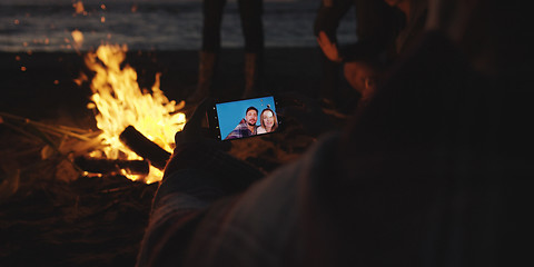 Image showing Couple taking photos beside campfire on beach