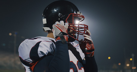 Image showing American Football Player Putting On Helmet on large stadium with