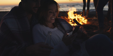 Image showing Couple enjoying bonfire with friends on beach