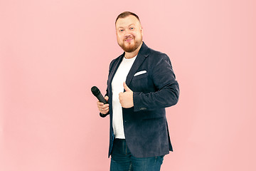 Image showing Young man with microphone on pink background, leading with microphone