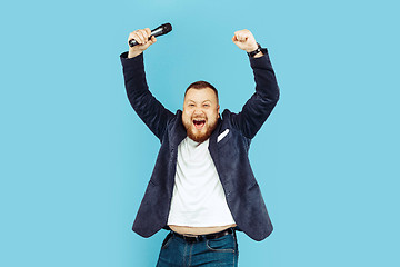 Image showing Young man with microphone on blue background, leading concept