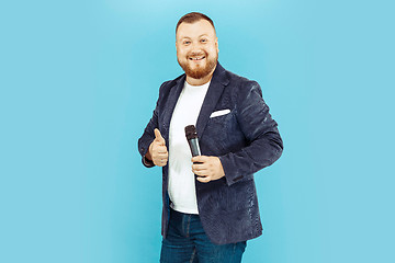 Image showing Young man with microphone on blue background, leading concept