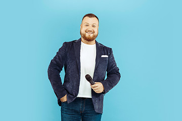 Image showing Young man with microphone on blue background, leading concept