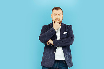 Image showing Young man with microphone on blue background, leading concept