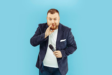 Image showing Young man with microphone on blue background, leading concept