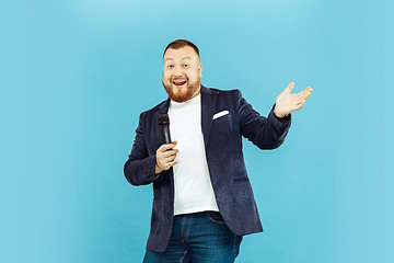 Image showing Young man with microphone on blue background, leading concept