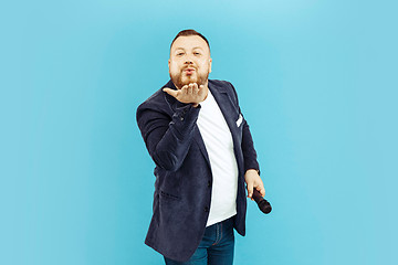 Image showing Young man with microphone on blue background, leading concept