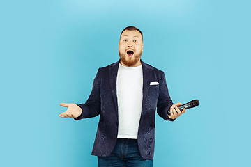 Image showing Young man with microphone on blue background, leading concept