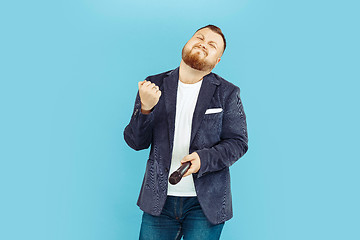 Image showing Young man with microphone on blue background, leading concept