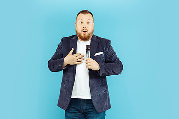 Image showing Young man with microphone on blue background, leading concept