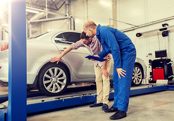 Image showing auto mechanic with clipboard and man at car shop