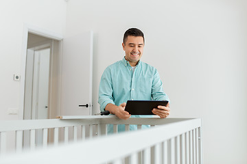 Image showing father with tablet pc assembling baby bed at home