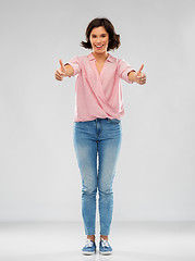 Image showing young woman in shirt and jeans showing thumbs up