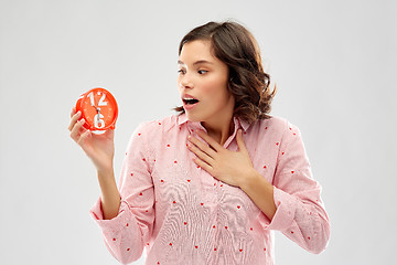 Image showing shocked young woman in pajama with alarm clock