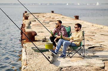 Image showing happy friends fishing and drinking beer on pier