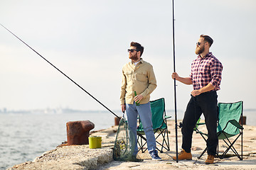 Image showing happy friends with fishing rods and beer on pier