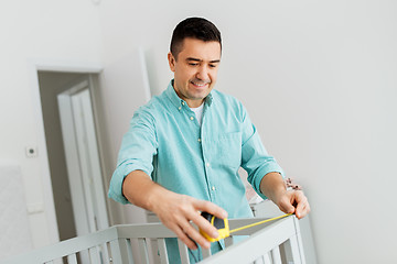 Image showing father with tablet pc and ruler measuring baby bed